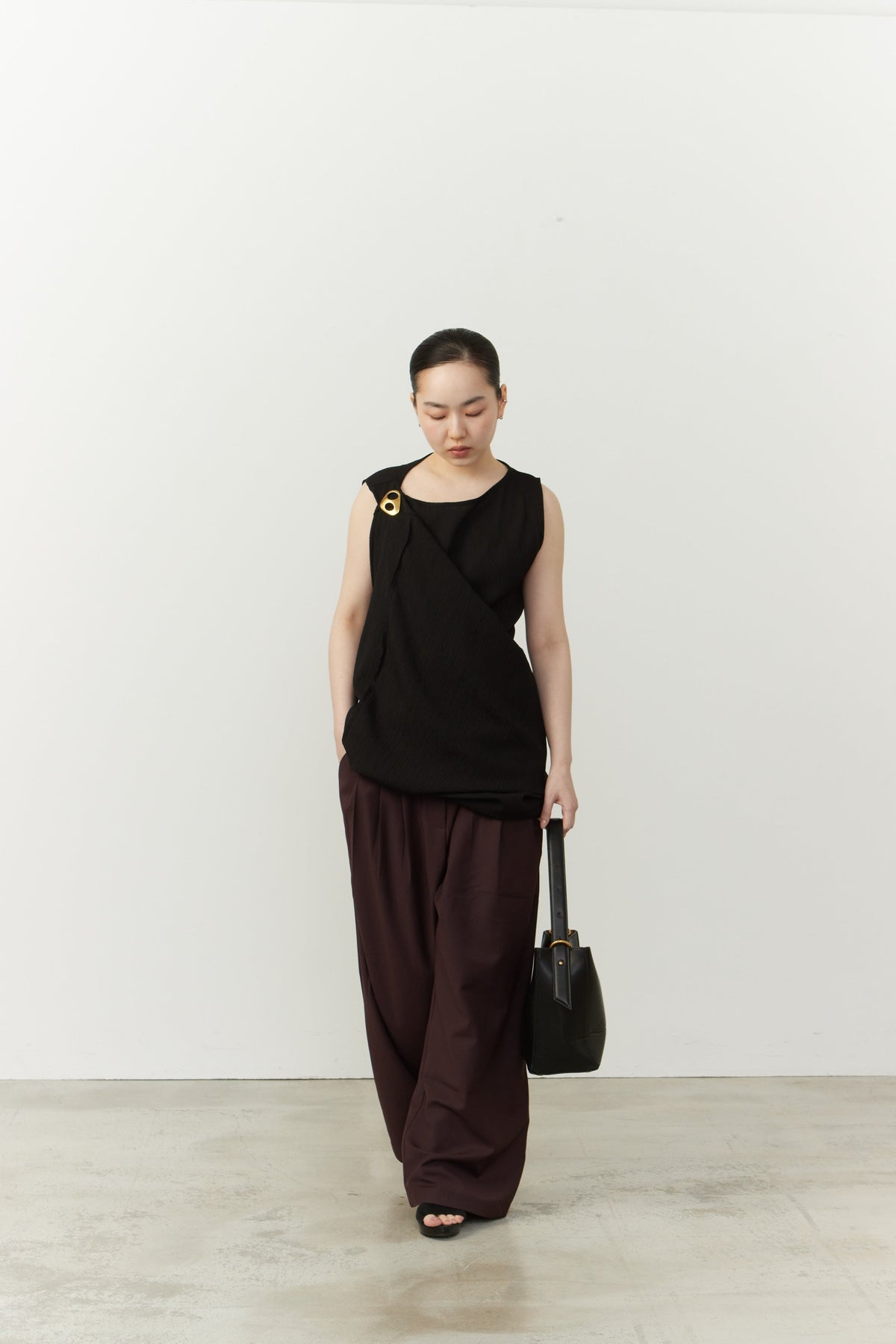 Model wearing a black sleeveless top, adorned with a Kitdo MiniMagni in Satin Glow at the neckline.
